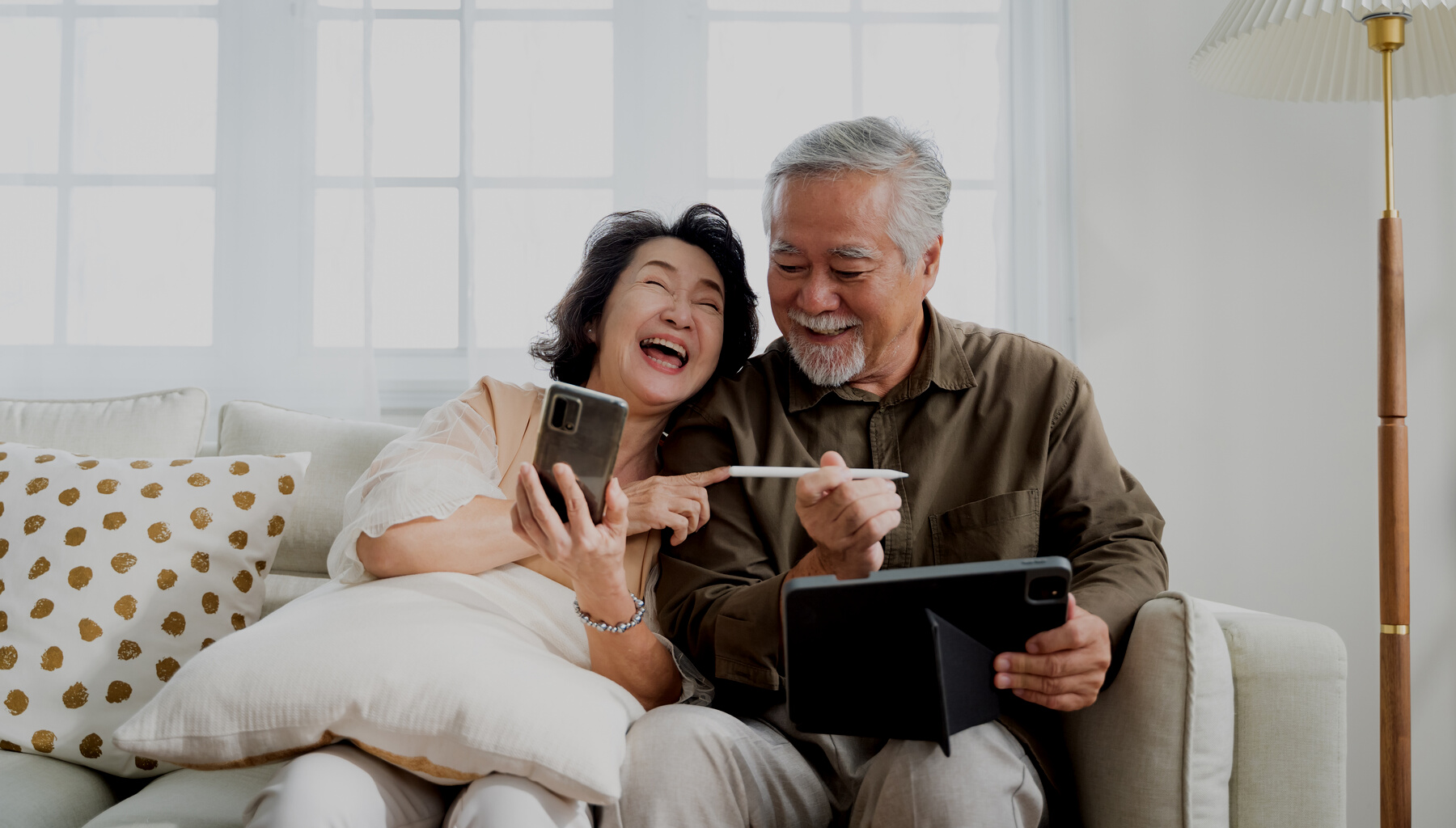 Senior Couple Happily Using Phone and Tablet